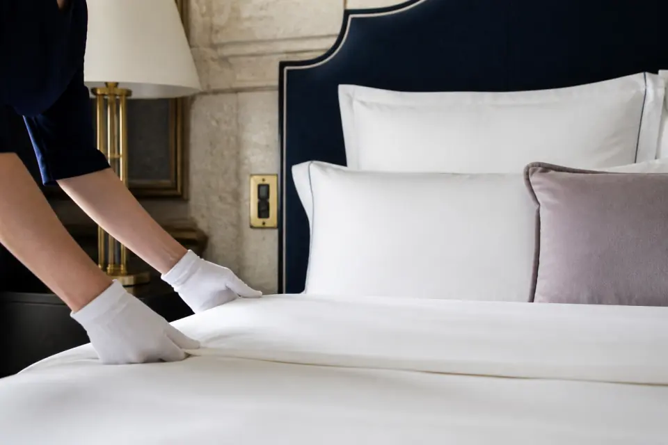 Préparation minutieuse du linge de lit dans une chambre d’hôtel
